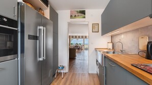 A modern kitchen with stainless steel appliances, a wooden countertop, and a view to a dining area. - Apartment 'Rheinblick Am Rheinsteig' with Mountain View, Wi-Fi and Air Conditioning (Urbar)