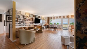 A spacious living area with a wooden floor, a sofa, a dining table, and a TV mounted on the wall. - Apartment 'Rheinblick Am Rheinsteig' with Mountain View, Wi-Fi and Air Conditioning (Urbar)
