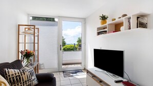 Un salon moderne avec un canapé, un téléviseur et des étagères.