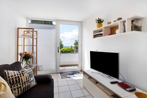En moderne stue med sofa, fjernsyn og reoler.