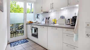 Une cuisine moderne avec des armoires blanches, un four encastré et une grande fenêtre.