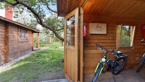 A wooden cabin with a bicycle parked inside. - Holiday Home 'Blockhütte' with Private Terrace and Private Garden (Fürstenwalde/Spree)