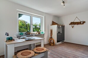 A kitchen with a dining table, a window, a refrigerator, and a wall-mounted decoration. - Apartment 'Ferienwohnung Schwarzwaldmädel' with Private Terrace, Private Garden and Wi-Fi (Seelbach)