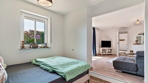 A bedroom with a bed, a window, a television, and a sofa.