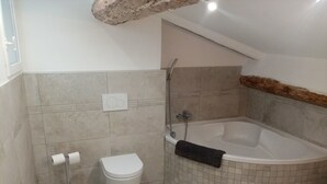 Une salle de bain moderne équipée d’une baignoire, de toilettes et d’un porte-serviettes.