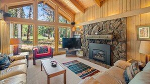 Una sala de estar acogedora con chimenea de piedra, ventanas amplias y un espacio de estar confortable.