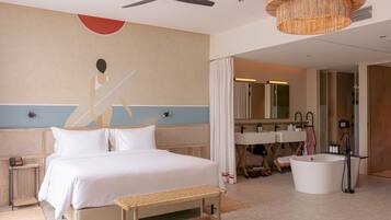 A hotel room with a bed, bedside table, bench, and a large mirror.