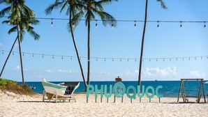 A beach with a boat, a swing set, and palm trees.
