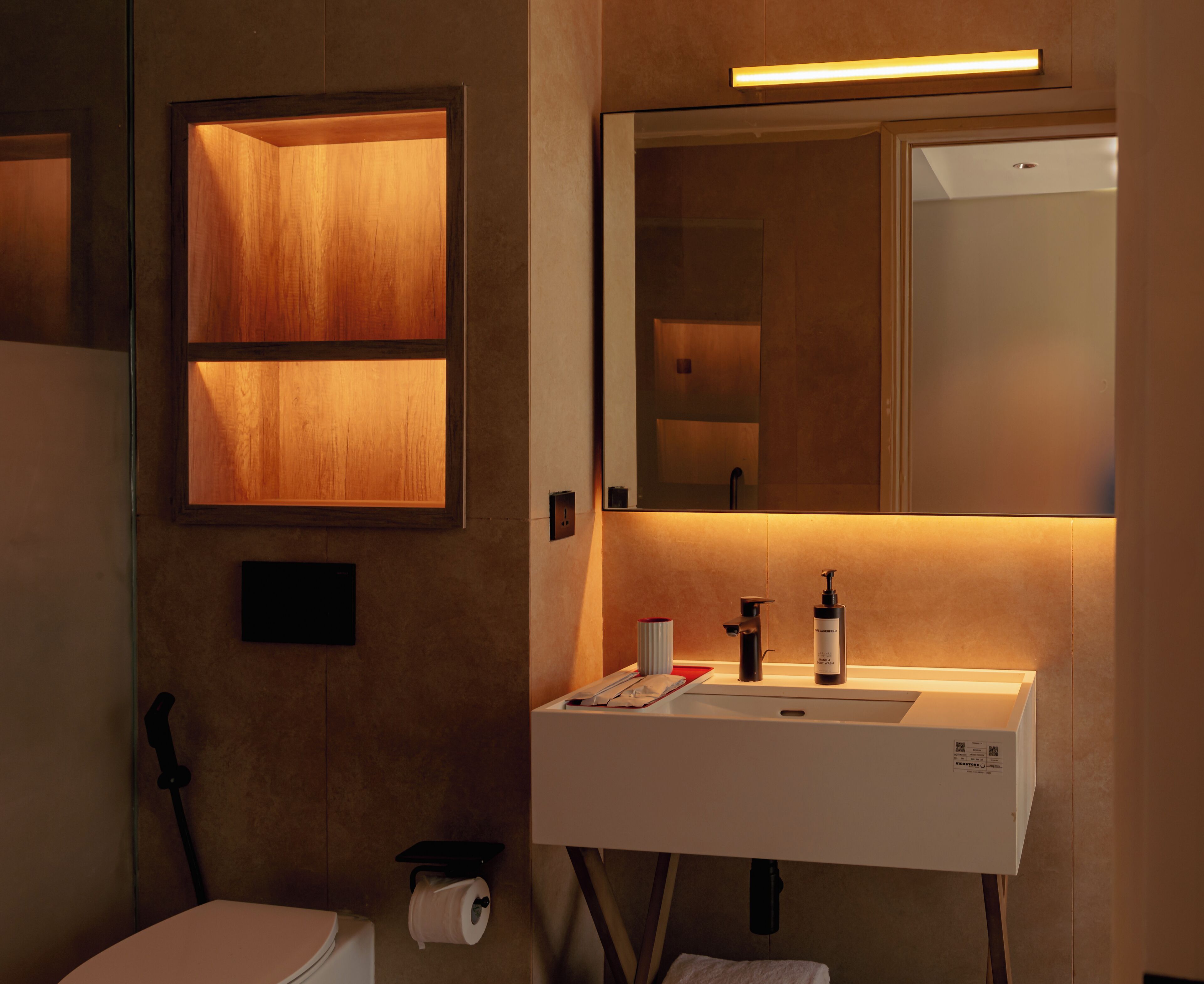 A modern bathroom with a white sink, a mirror, and a wooden panel on the wall.