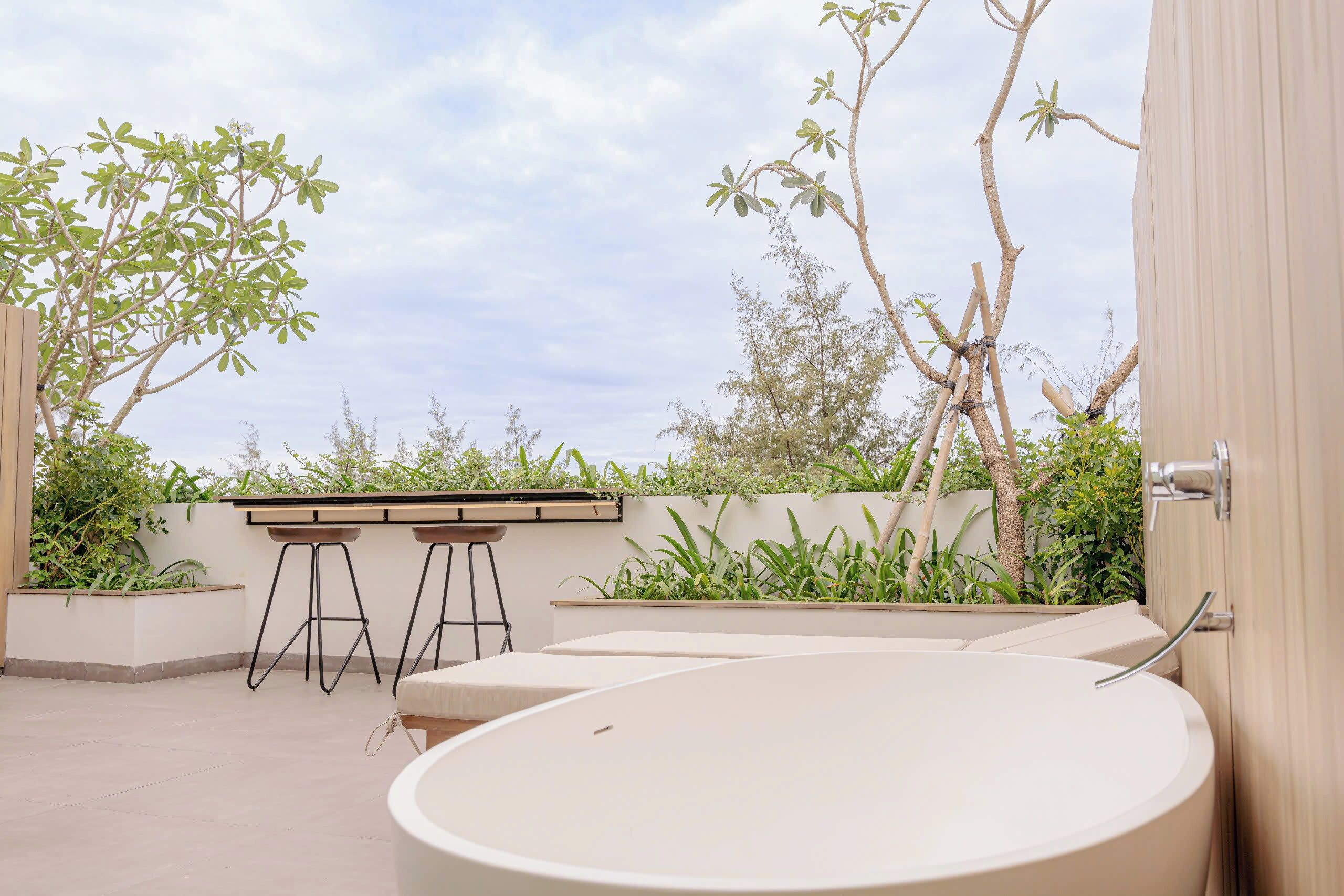 A modern outdoor pool area with a seating arrangement and a view of the sky.