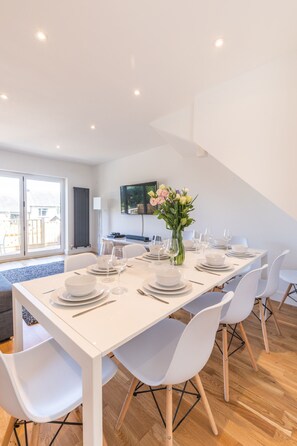 A modern dining area with a white table set for six, surrounded by white chairs. - Modern 4Bed Seaside Escape * With Parking* (Brighton and Hove)