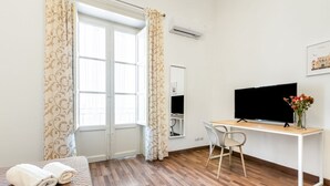 A room with a bed, a desk, a chair, a TV, and a window with curtains. - GuestHost - Modern Two-Levels Apartment with Balconies! (Palermo)