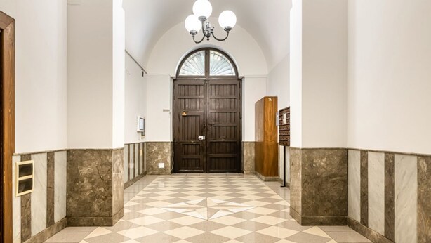 A hallway with a checkered floor, a large wooden door, and a chandelier. - GuestHost - Modern Two-Levels Apartment with Balconies! (Palermo)