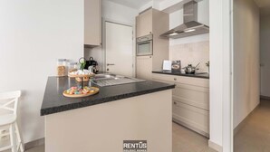 A modern kitchen with a central island, built-in oven, and stainless steel range hood. - Seange - with beautiful view and many facilities (Nieuwpoort)