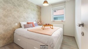A bedroom with a bed, a bedside table with candles, a window, and a radiator. - Seange - with beautiful view and many facilities (Nieuwpoort)