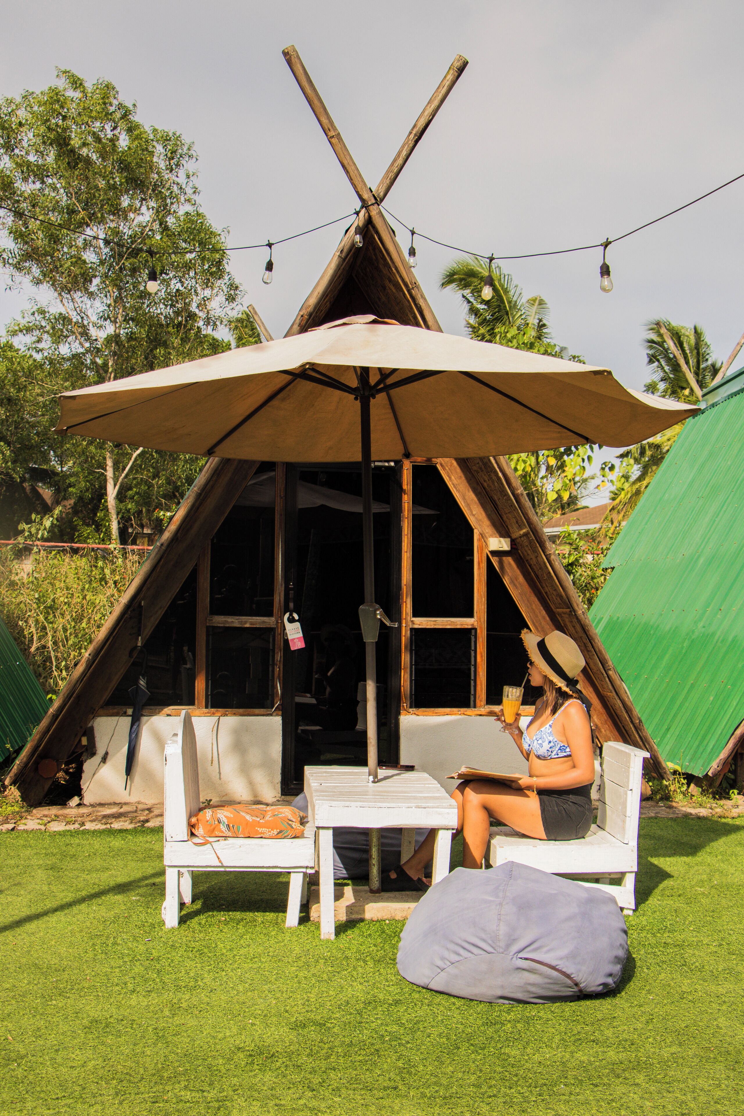 Une structure en forme de tipi, avec une table et des chaises placées sous une marquise, le tout entouré de verdure.