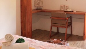 Ein kleiner, gemütlicher Raum mit einem Holztisch, einem Stuhl, ordentlich zusammengelegtem Handtuch und einer Wanddekoration.