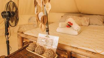 A bed with a wooden headboard, a fan, and a menu on a wooden table.