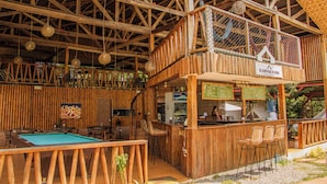 A wooden bar area with a pool table, seating, and a sign for Glamping Aloha. - Glamping Alona (Panglao)