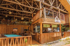 A wooden bar area with a pool table, seating, and a sign for Glamping Aloha. - Glamping Alona (Panglao)