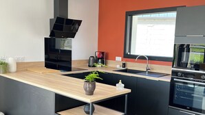 Eine moderne Küche mit einer zentralen Kochinsel, schwarzen Schränken, einer Holz Arbeitsplatte und einem Fenster für natürliches Licht.