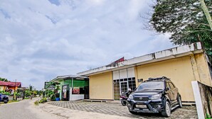 Ein Gebäude mit befestigtem Eingangsbereich, einem geparkten SUV und einem Motorrad.