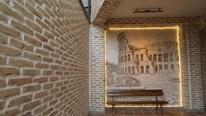 A brick-walled corridor with a bench and a mural of the Colosseum. - Arka boutique hotel (Samarkand)