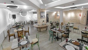 A modern dining area with round tables, chairs, and a mix of wooden and upholstered seating. - Arka boutique hotel (Samarkand)