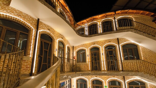 A multi-story building with brick walls and arched windows, featuring a staircase and balconies. - Arka boutique hotel (Samarkand)