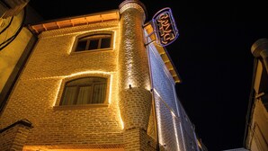 A brick building with illuminated windows and a neon sign. - Arka boutique hotel (Samarkand)