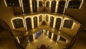 A multi-level atrium with a central seating area, surrounded by balconies and arched windows. - Arka boutique hotel (Samarkand)