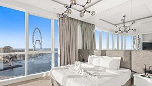 Ein modernes Hotelzimmer mit einem großen Bett, Blick auf ein Riesenrad und Stadtlandschaft.