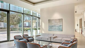 A modern lobby with a large window, a grey sofa, and matching armchairs.