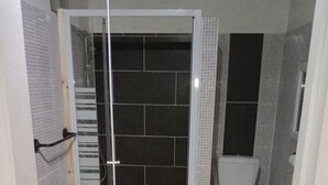 Kylpyhuone, jossa on suihku, wc ja laatoitettu lattia.