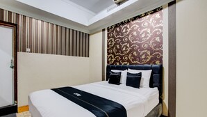 Un lit bien fait, recouvert d’une couvre-lit noire et blanche, avec une tête de lit ornée d’un motif floral et un mur à rayures derrière.