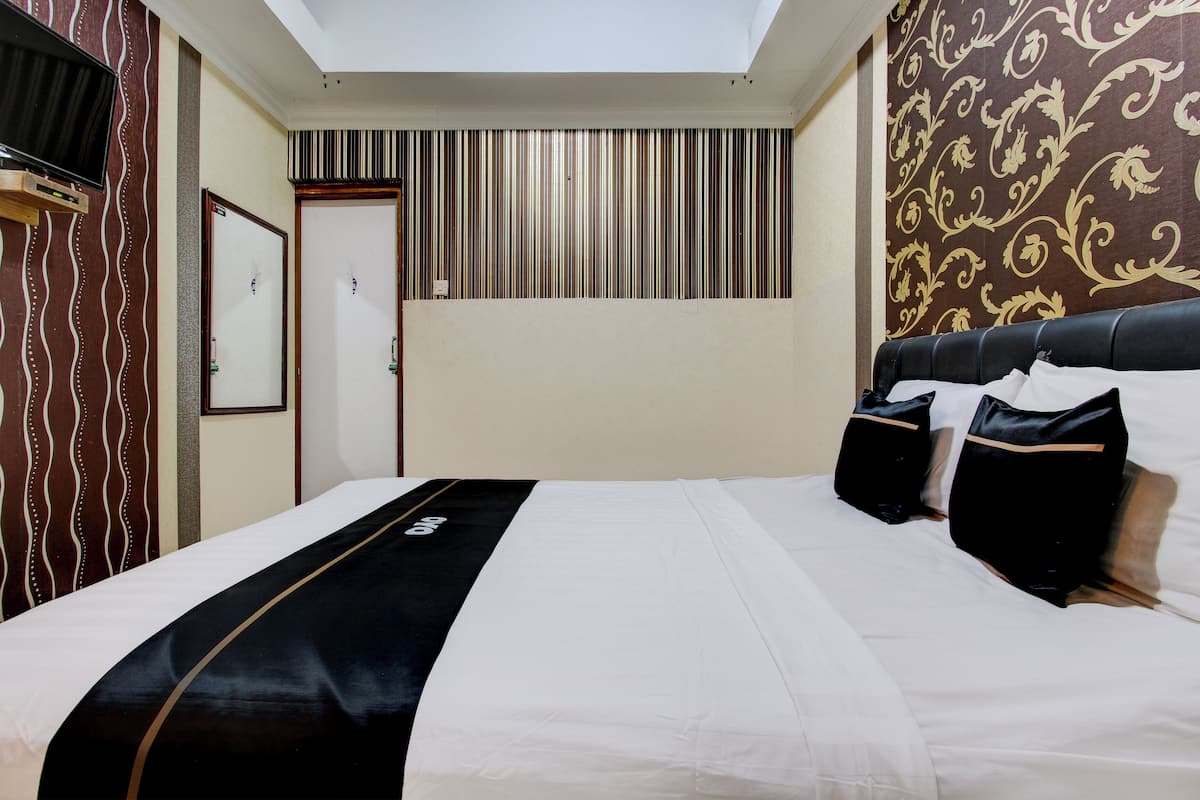 Una habitación de hotel con una cama, un televisor montado en la pared y un diseño de pared a rayas.