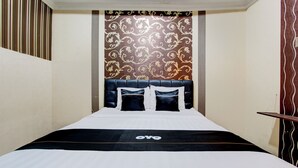 Une chambre d’hôtel avec un lit, une tête de lit et un mur décoré d’un motif.