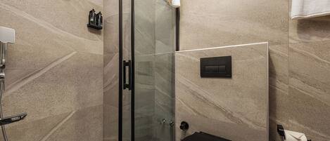 A modern bathroom with a glass-enclosed shower, a black toilet, and a marble-tiled wall.