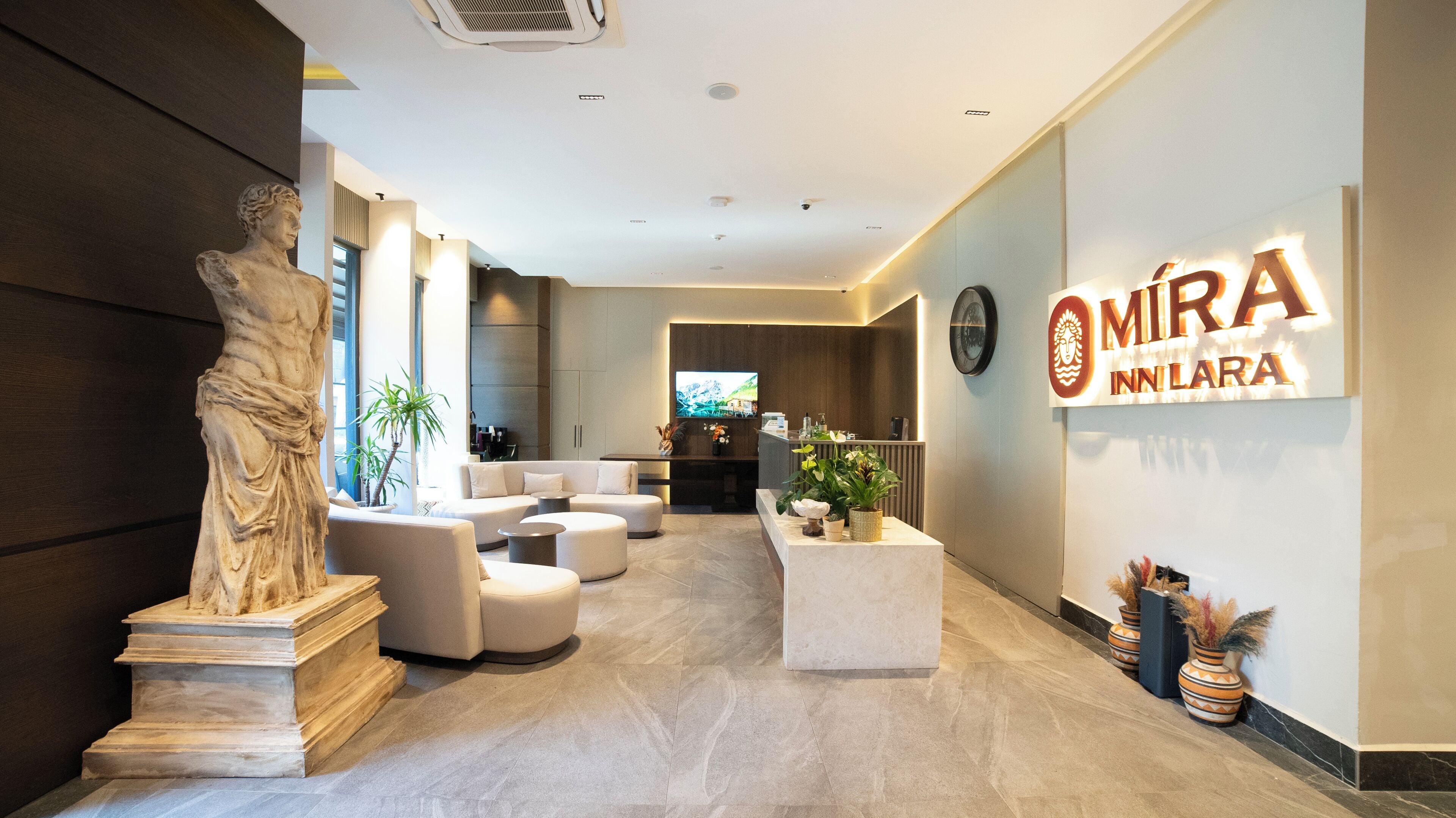 Un moderno vestíbulo de hotel con mostrador de recepción, zona de estar y una gran estatua.