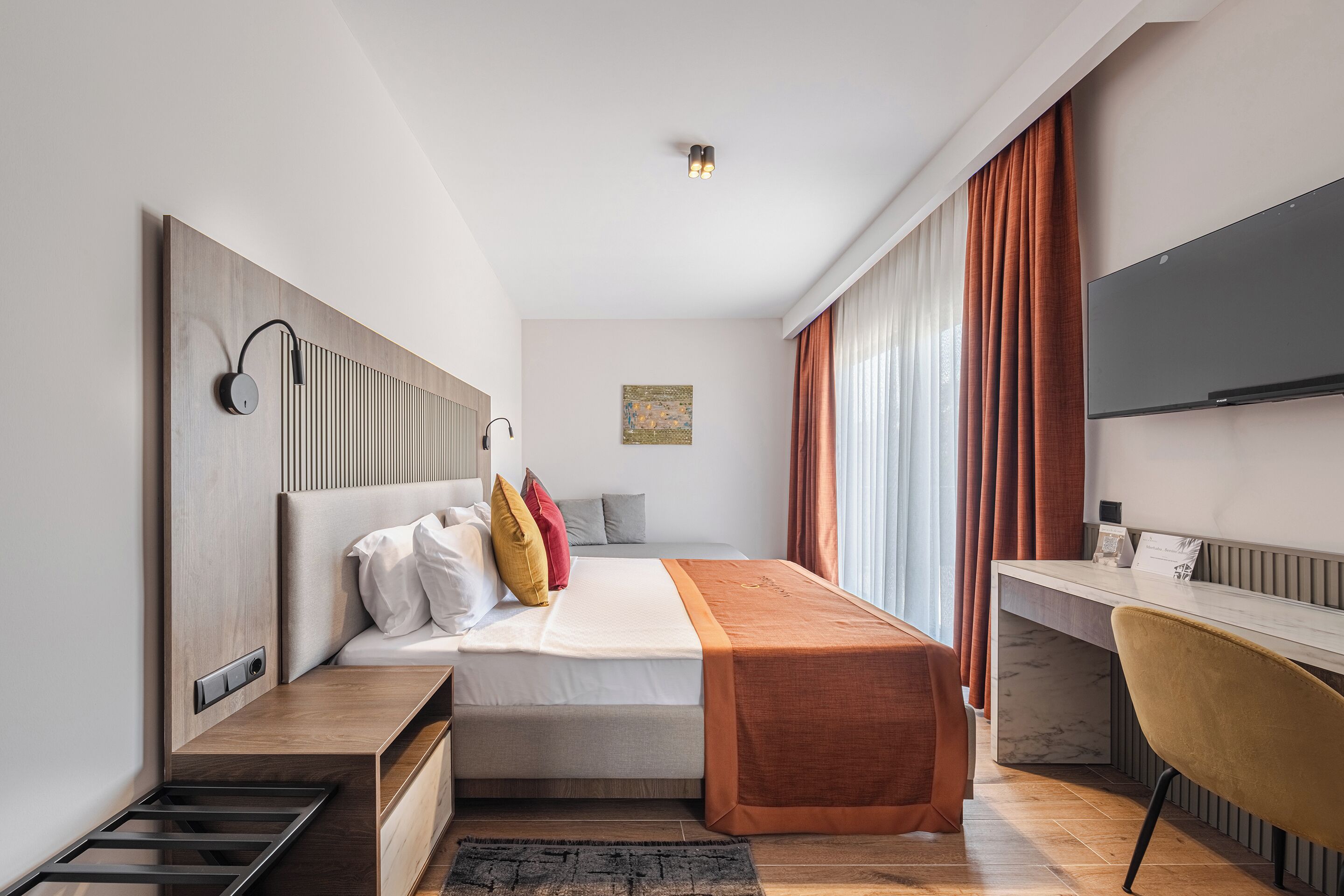 Una habitación de hotel moderna con cama, mesita de noche, escritorio y silla.