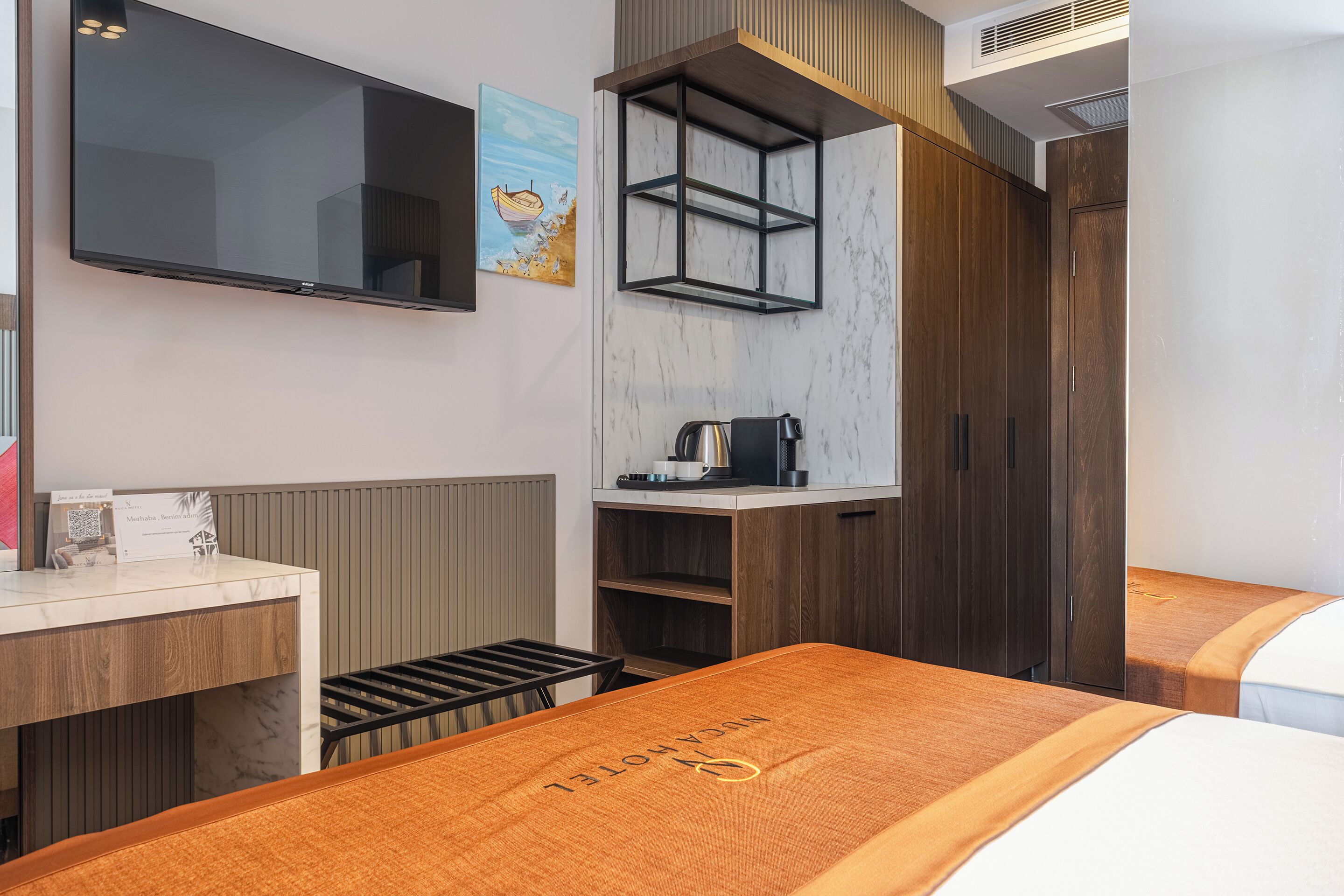 Ett hotellrum med en säng, ett skrivbord, en TV, en kaffemaskin och en garderob.