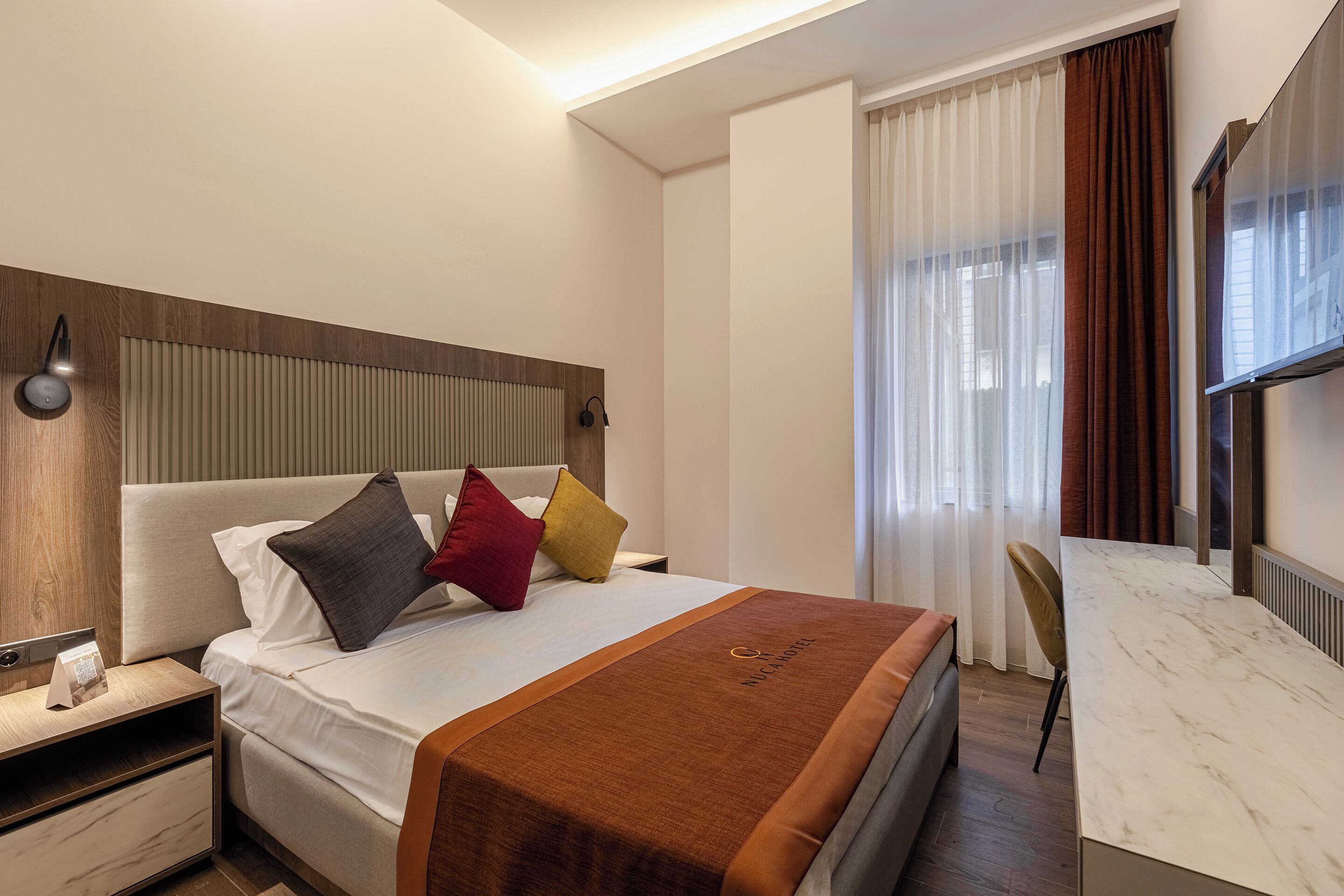 Una habitación de hotel con cama, mesita de noche y escritorio con silla.