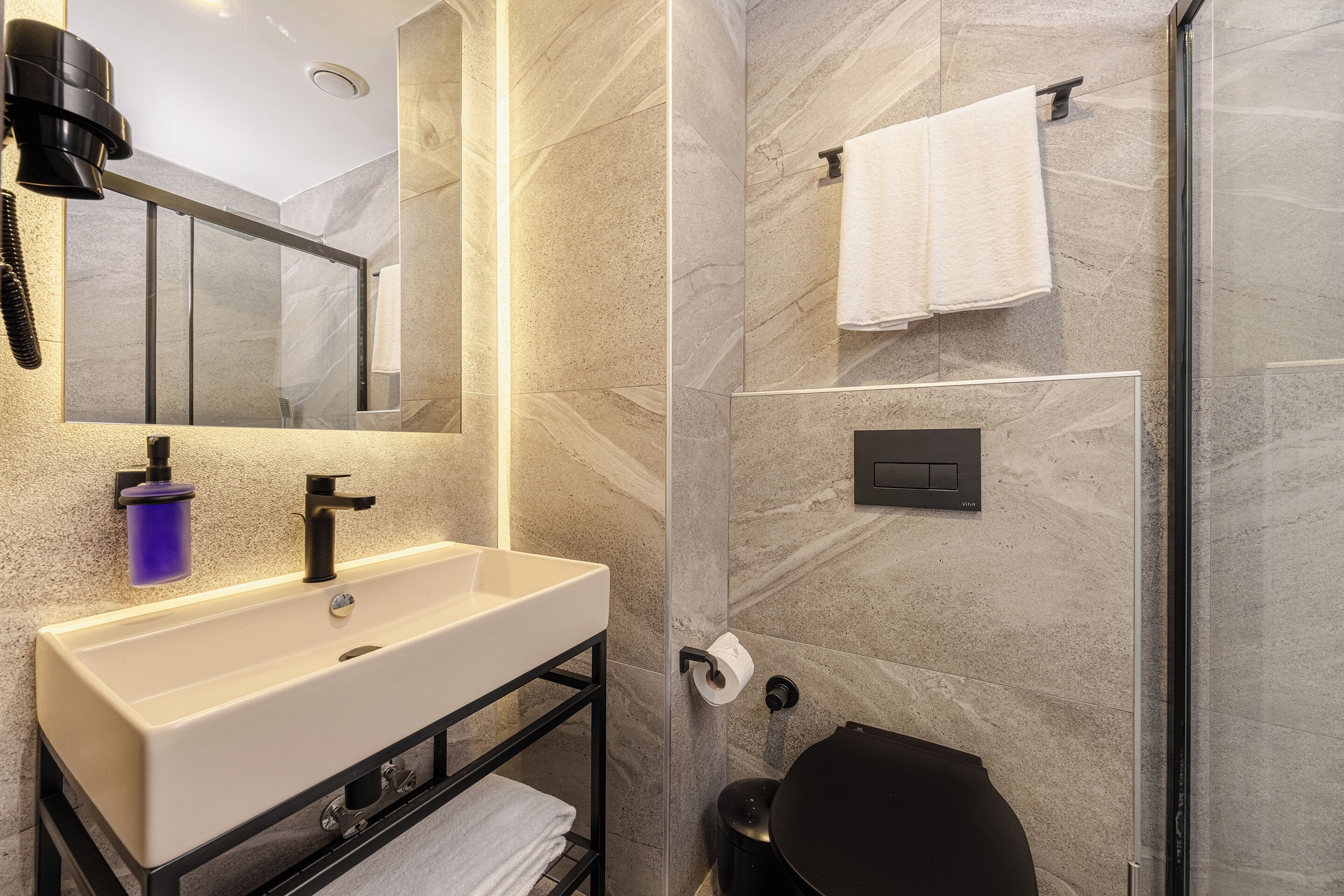 A modern bathroom with a large mirror, a sink, a toilet, and a shower area.