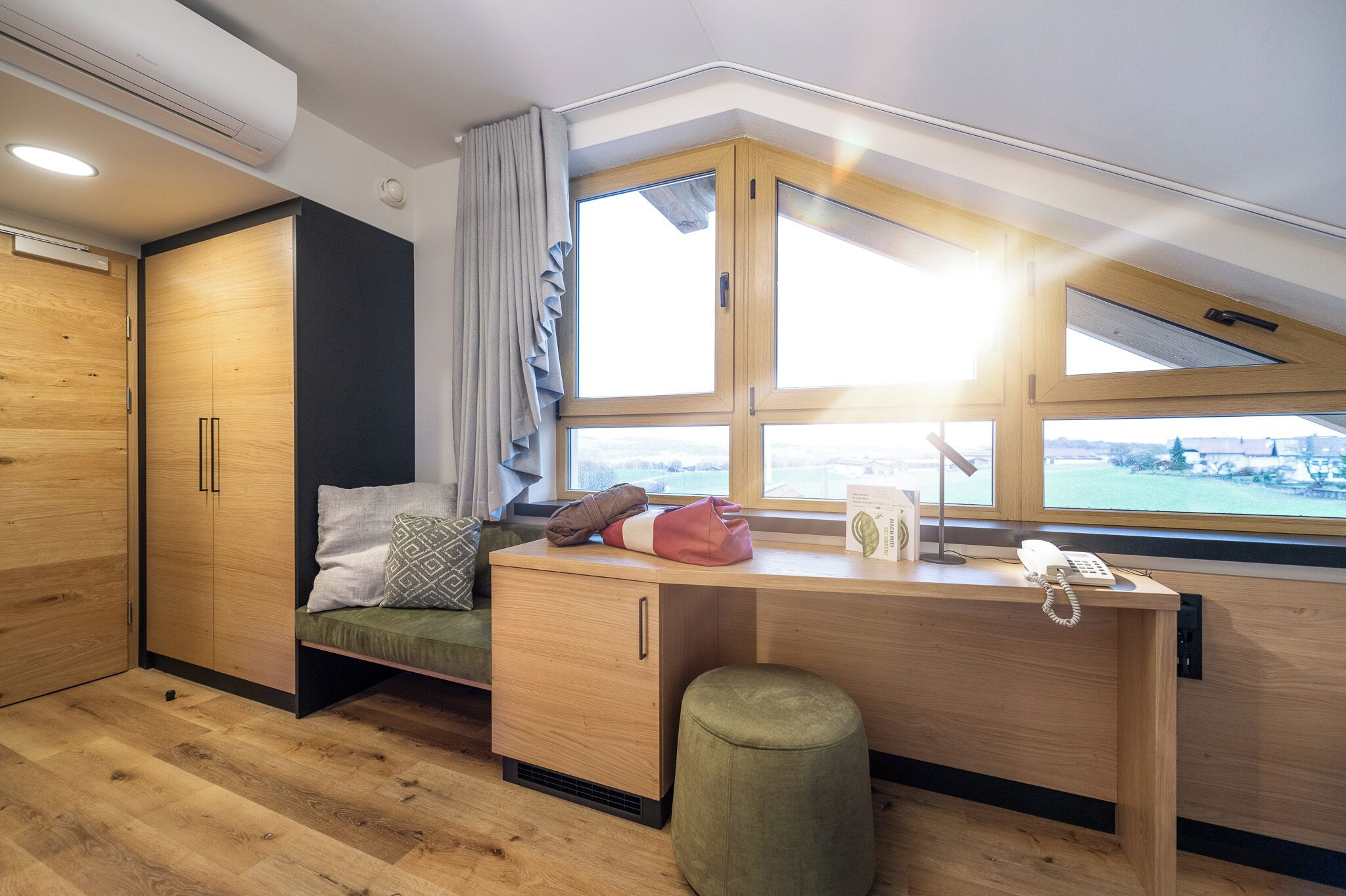 Ein kleines Zimmer mit Hochbett, Schreibtisch und Telefon, sowie Ausblick durch ein großes Fenster.