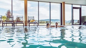 Una piscina con agua cristalina, rodeada de amplias ventanas con vistas al exterior.