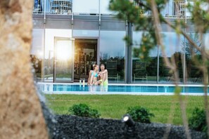 A modern building with a glass facade, a swimming pool, and a well-maintained lawn. - Landrefugium Obermüller (Untergriesbach)
