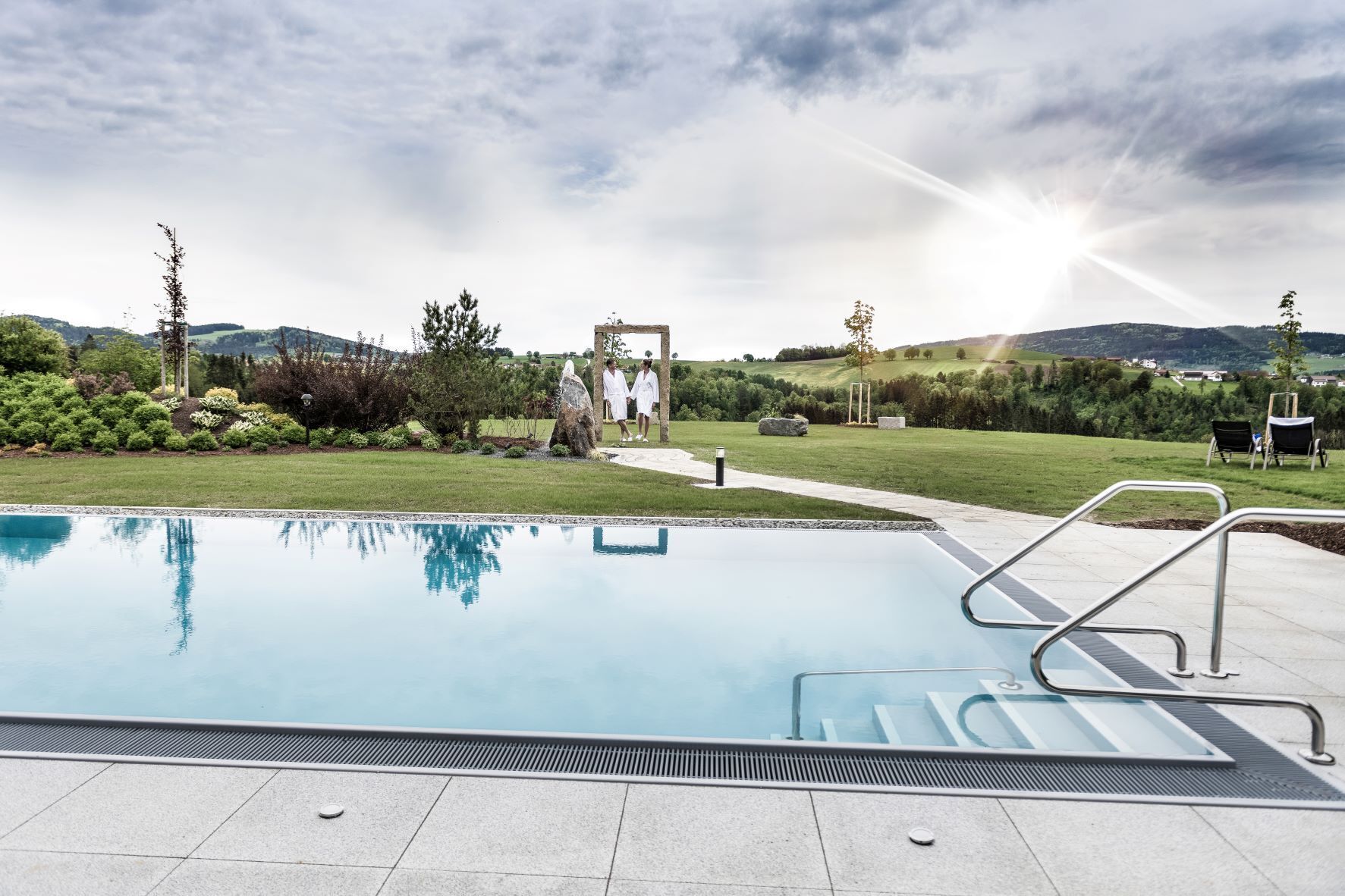 Una piscina con vistas despejadas del paisaje circundante, que incluye un área con césped y colinas a lo lejos.