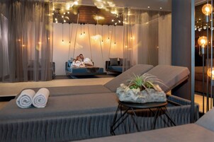 Un spa moderno con una camilla de masaje, un rincón de descanso y una iluminación ambiental.