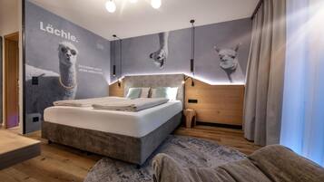Un dormitorio moderno con una cama grande, un cabecero con iluminación integrada, una obra de arte en la pared de un llama y suelo de madera.