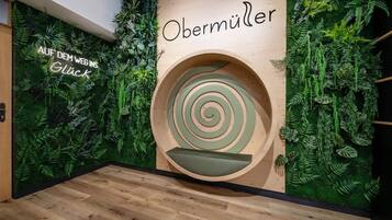 A room with a wooden wall, a spiral design, and green foliage.